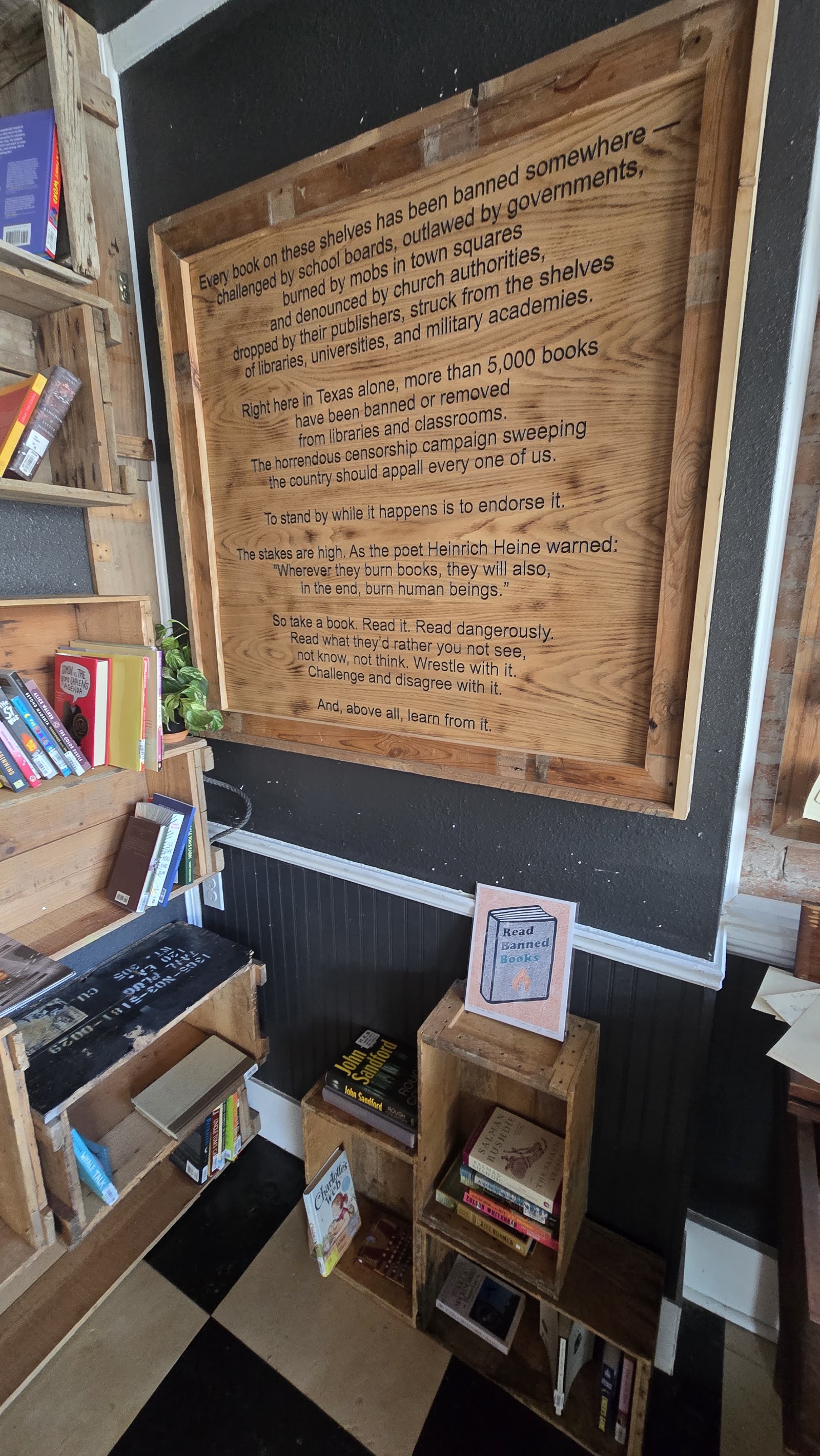 A large carved wooden plaque: the shop's banned-books manifesto, ending 'read dangerously… and, above all, learn from it.'